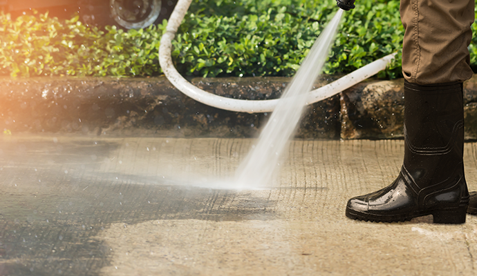 Expert cleaning a concrete driveway using professional equipment
