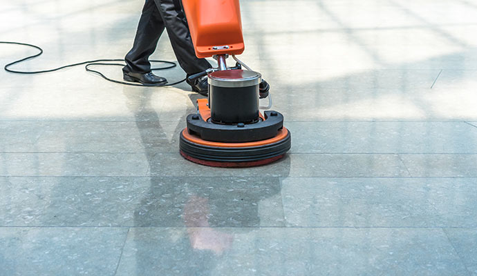 Worker is cleaning porcelain tile with a machine.