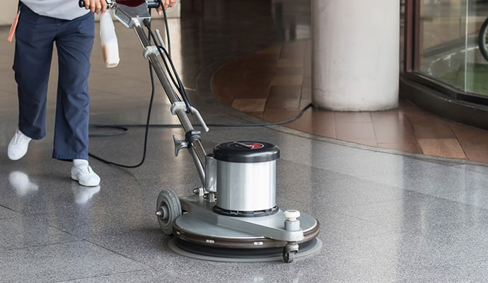 An expert cleaning a stone floor with a floor-cleaning machine